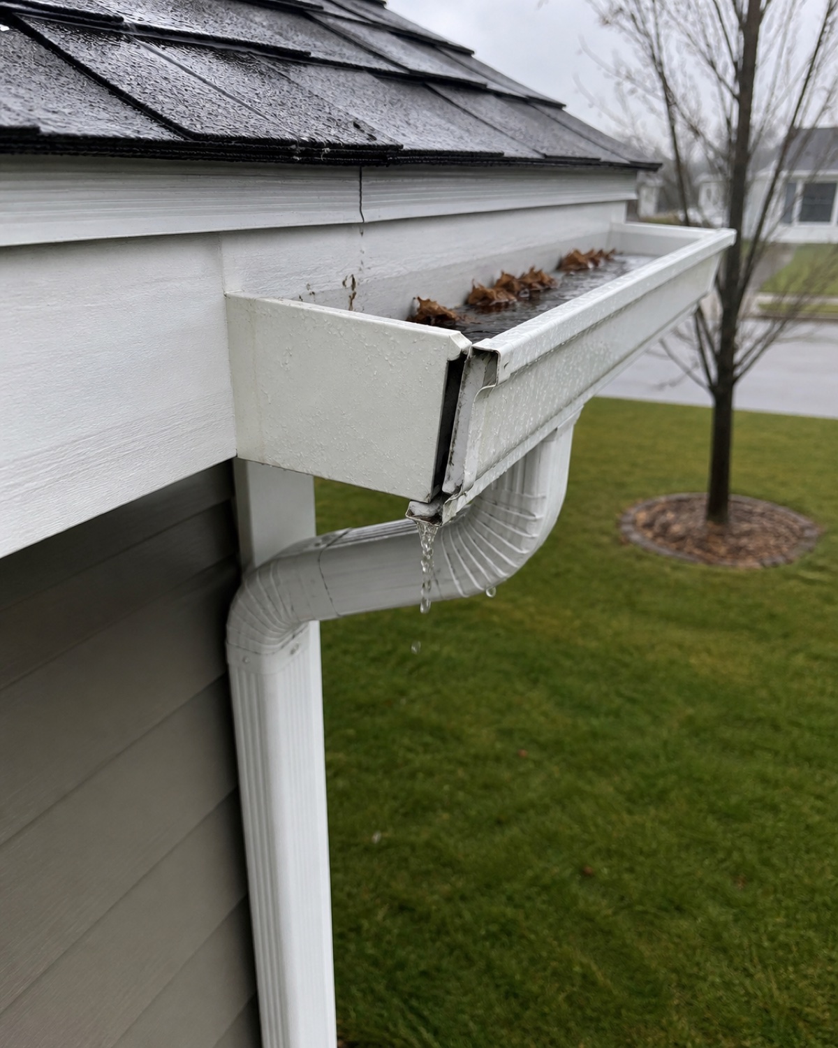 A loose residential gutter section with a leaking corner joint before repair